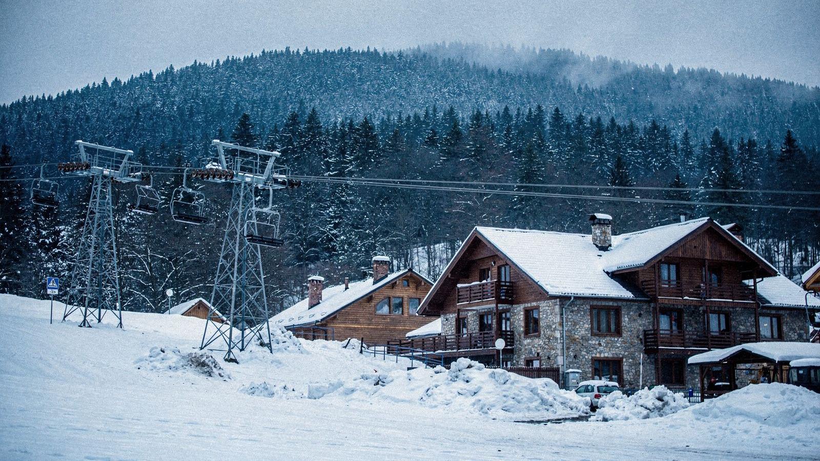 Chairlift and timber guesthouses above a snow-covered Carpathian mountain village