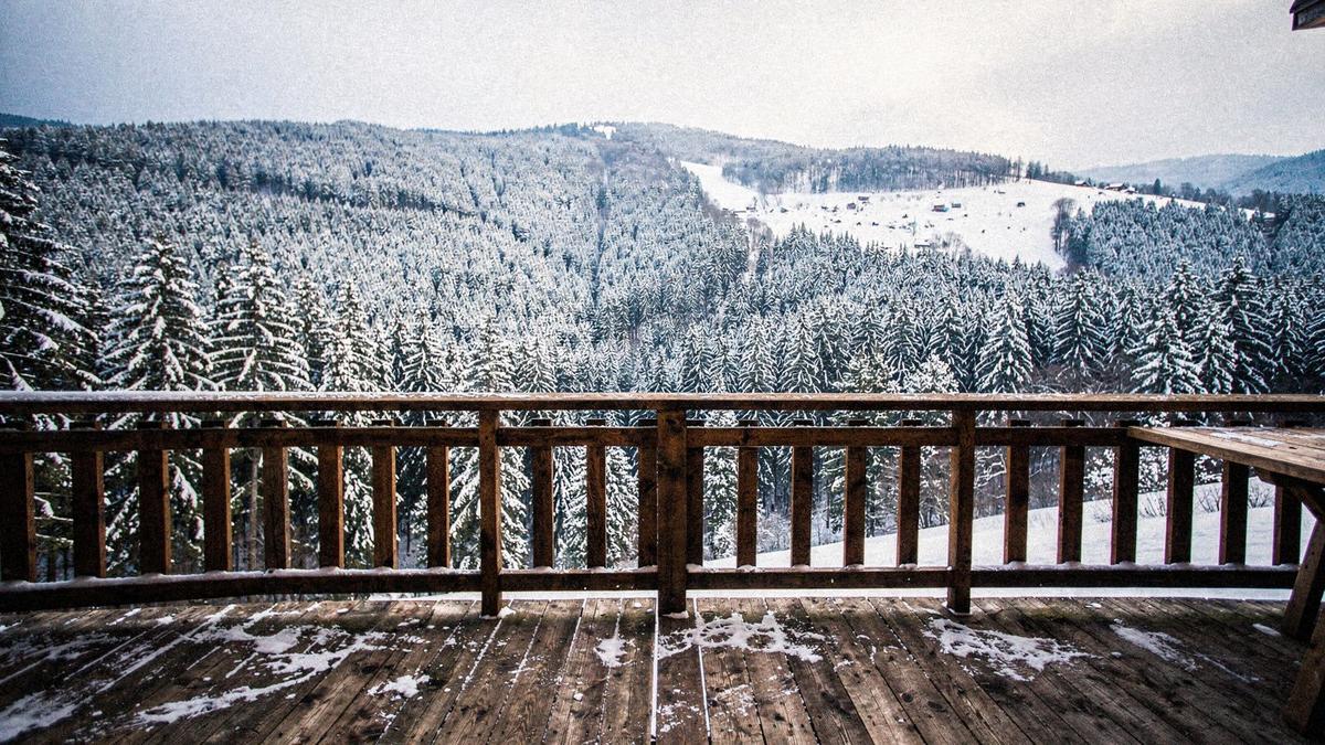 Wooden guesthouse veranda above a snowy Carpathian valley near Bukovel